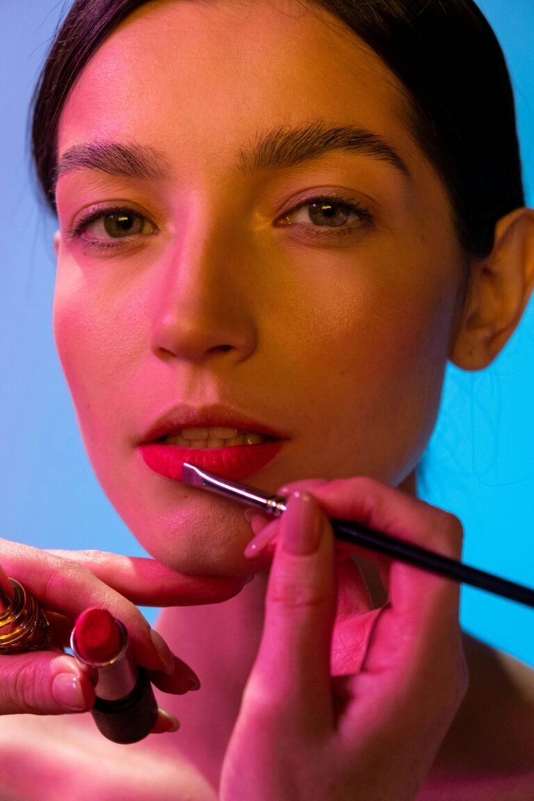All About Close-up of a young woman getting her lipstick applied by a makeup artist.